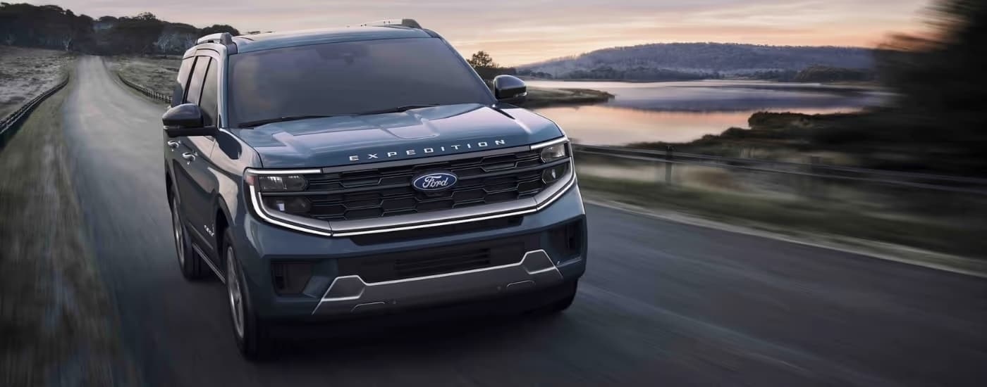 A blue 2025 Ford Expedition driving near water.