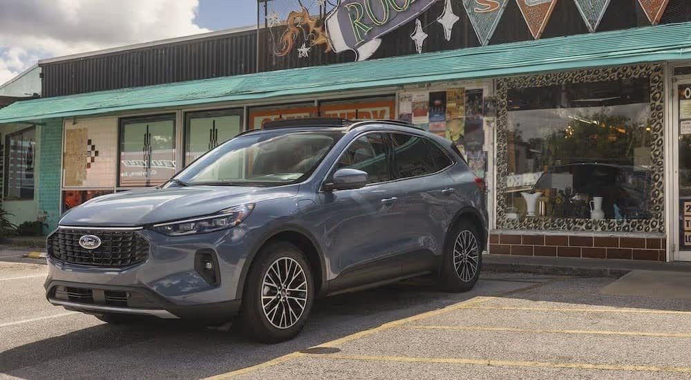 A blue 2025 Ford Escape is shown parked in front of a store.