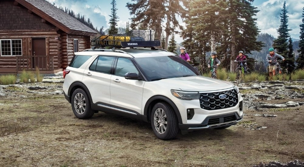 A white 2025 Ford Explorer parked near a cabin.