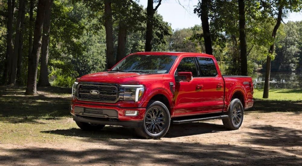 A red 2025 Ford F-150 Lariat is shown parked in the woods angled left.