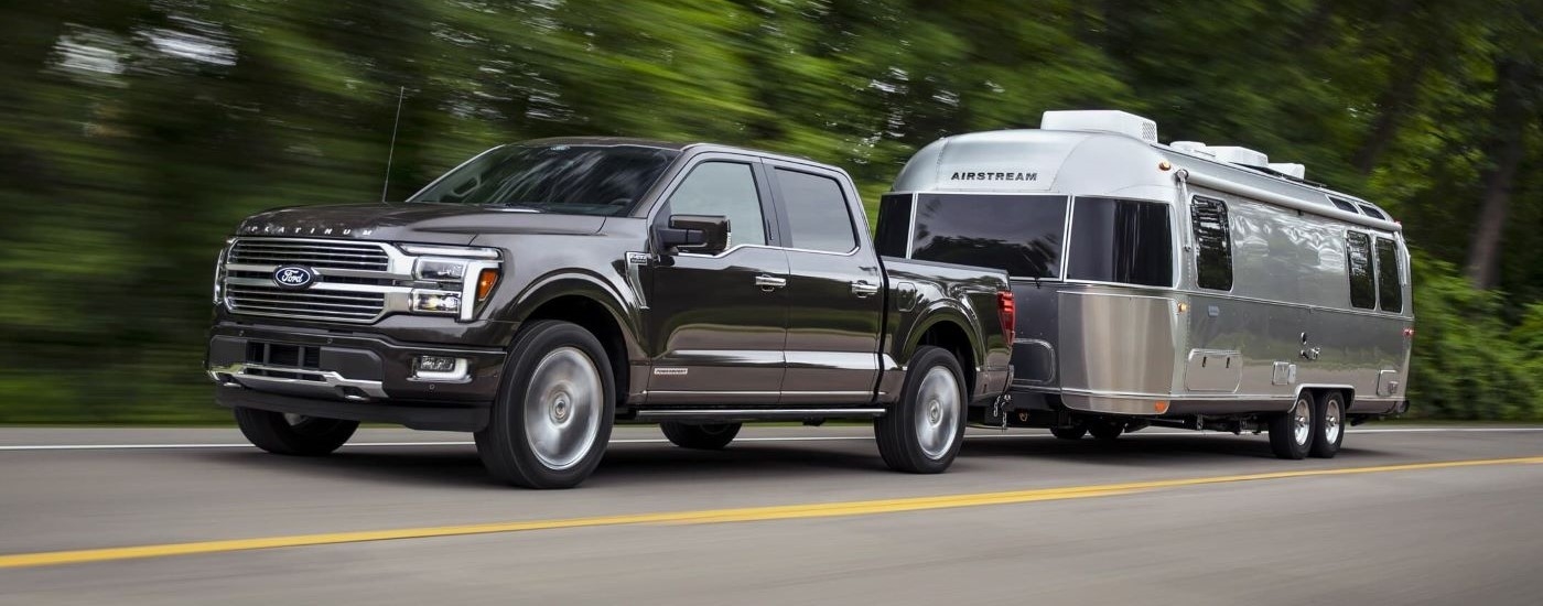 A grey 2023 Ford F-150 from the side while towing.