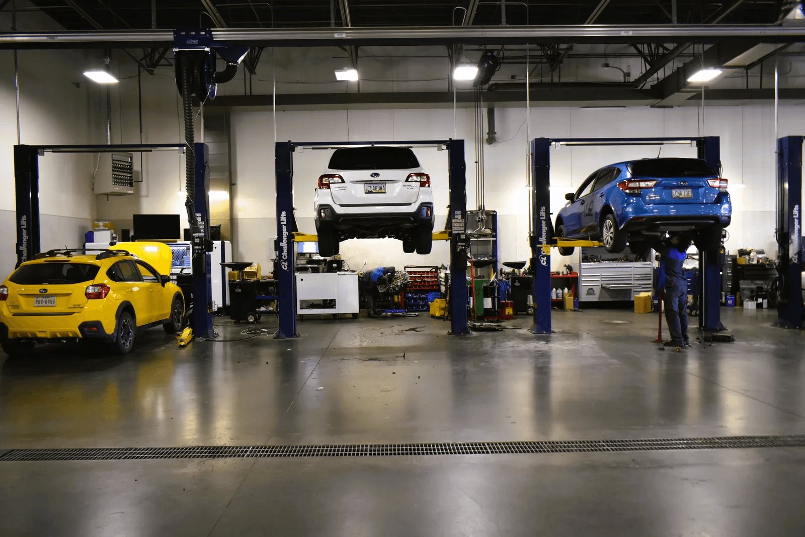 Inside the Findlay Subaru Prescott service bays, with Subarus on lifts and a technician at work