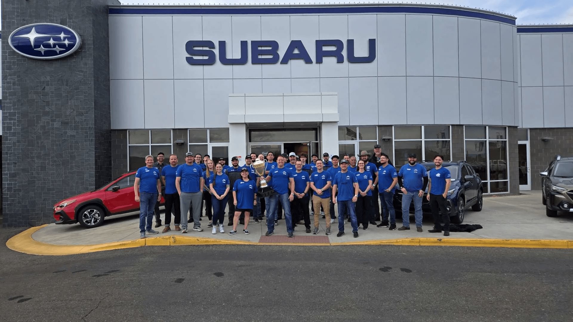 The Findlay Subaru Prescott team in branded shirts outside the dealership's Subaru showroom on Willow Creek Road