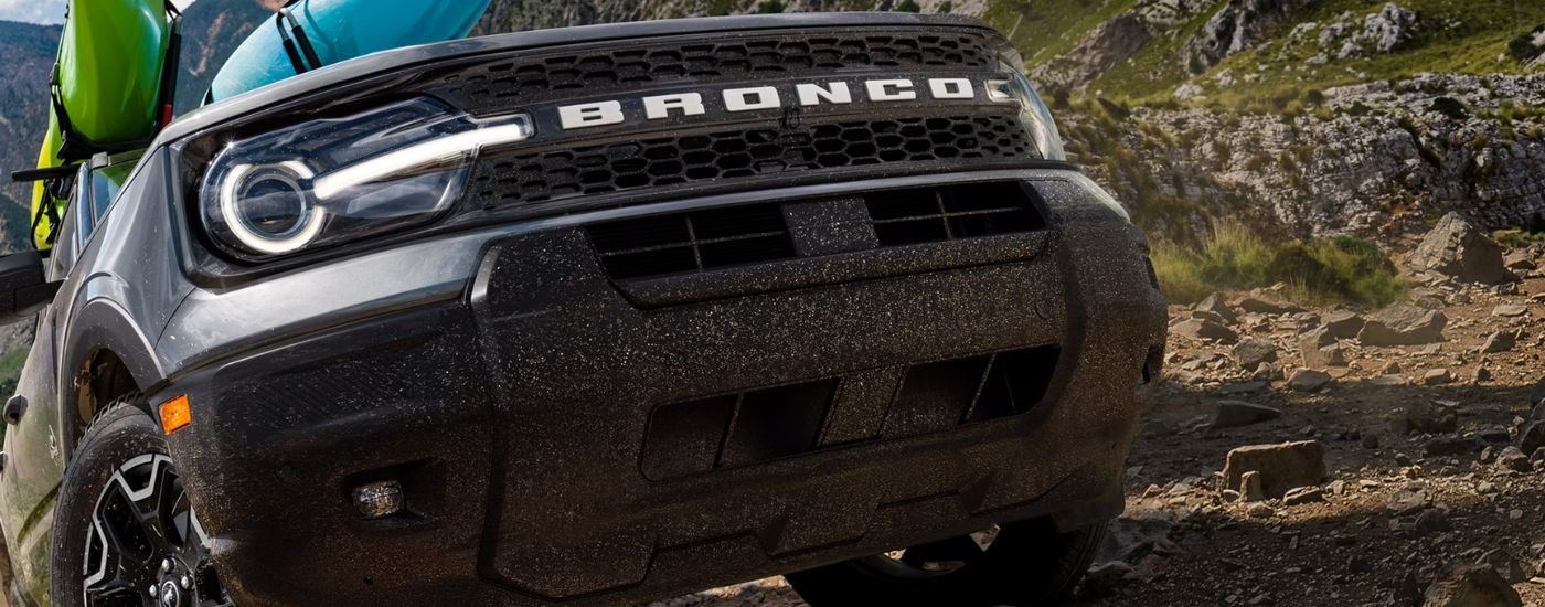 Close up of a black 2026 Ford Bronco Sport driving off-road with kayaks on the roof.