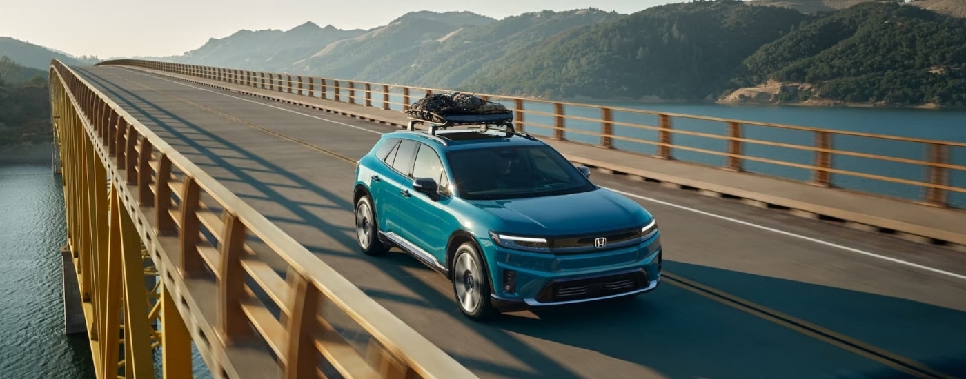 A blue 2024 Honda Prologue shown crossing a bridge over water.