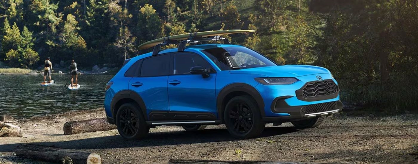Blue 2026 Honda HR-V with paddleboards on the roof parked near a lake.