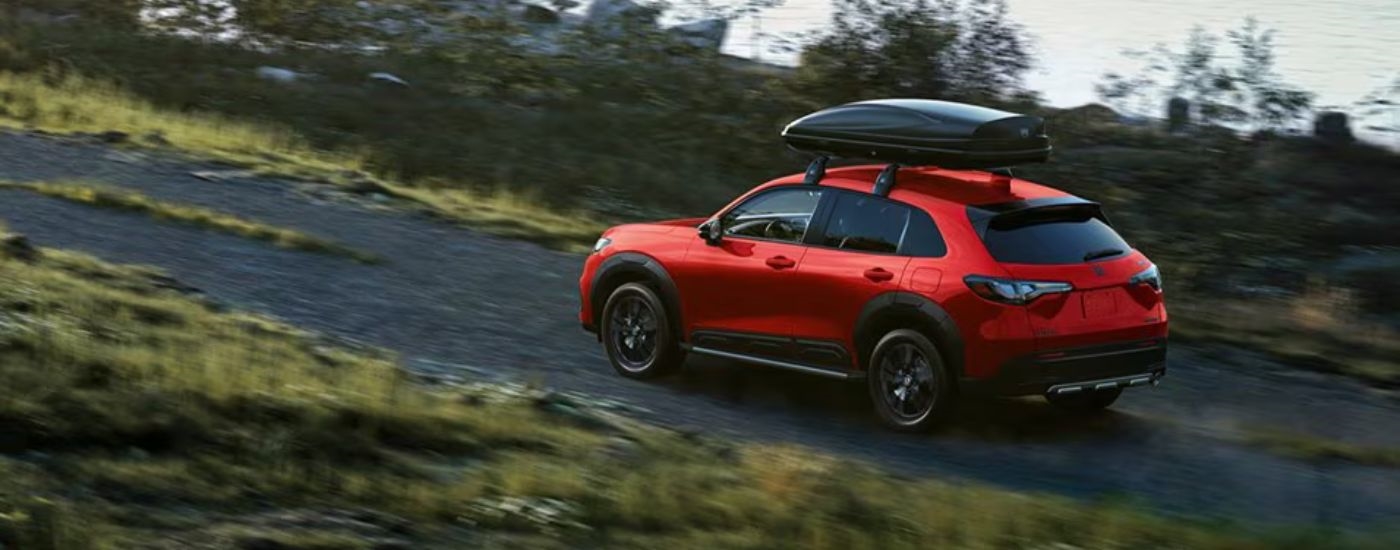 Red 2026 Honda HR-V with a luggage rack driving on an off-road trail.