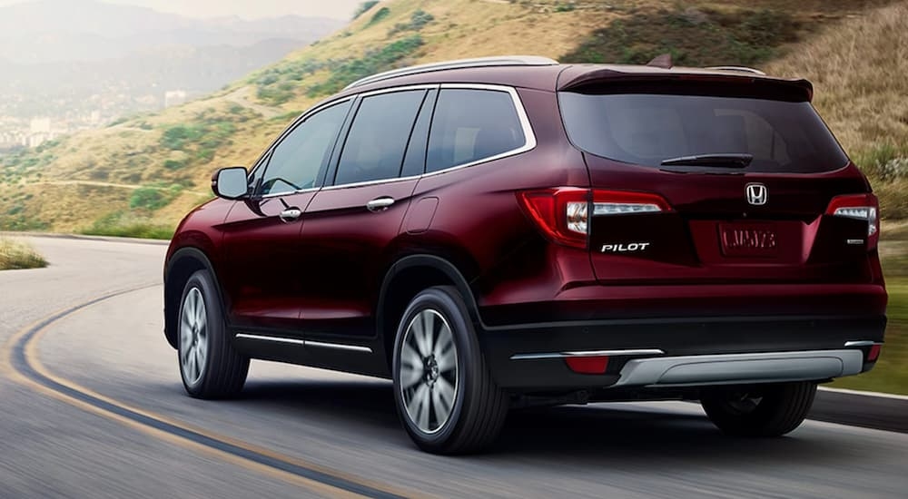 A maroon 2020 Honda Pilot Touring shown driving.