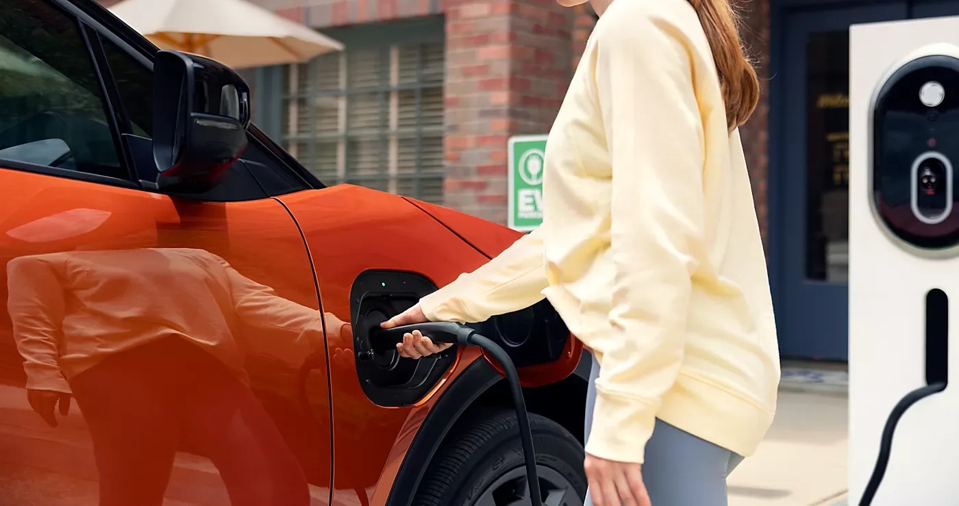 A driver plugging a charging cable into the 2027 Subaru Getaway at a public charging station.