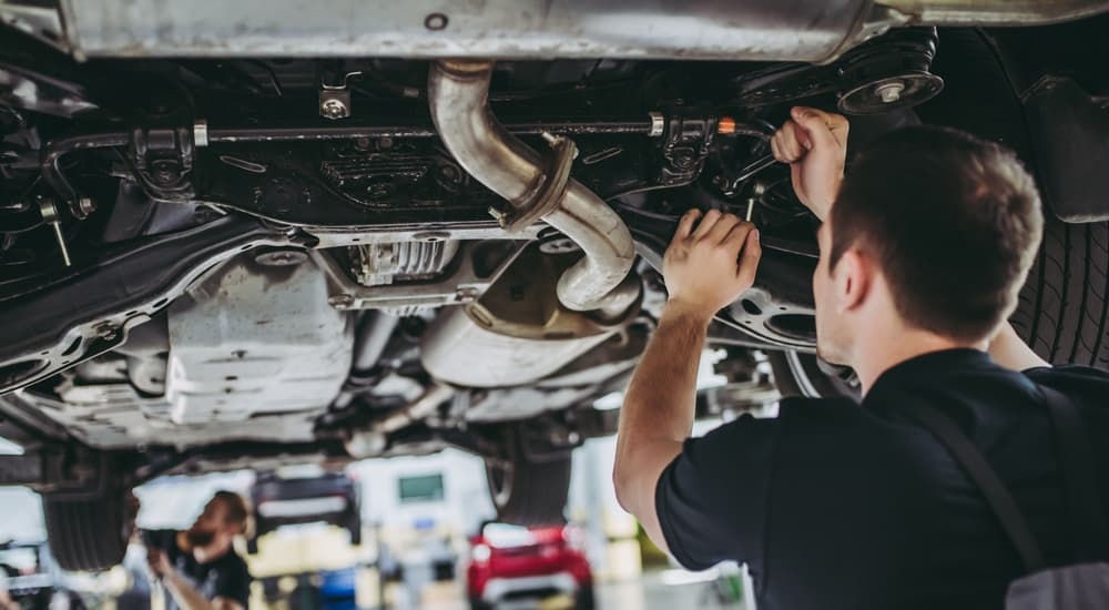 A service technician working on the undercarriage of a vehicle.