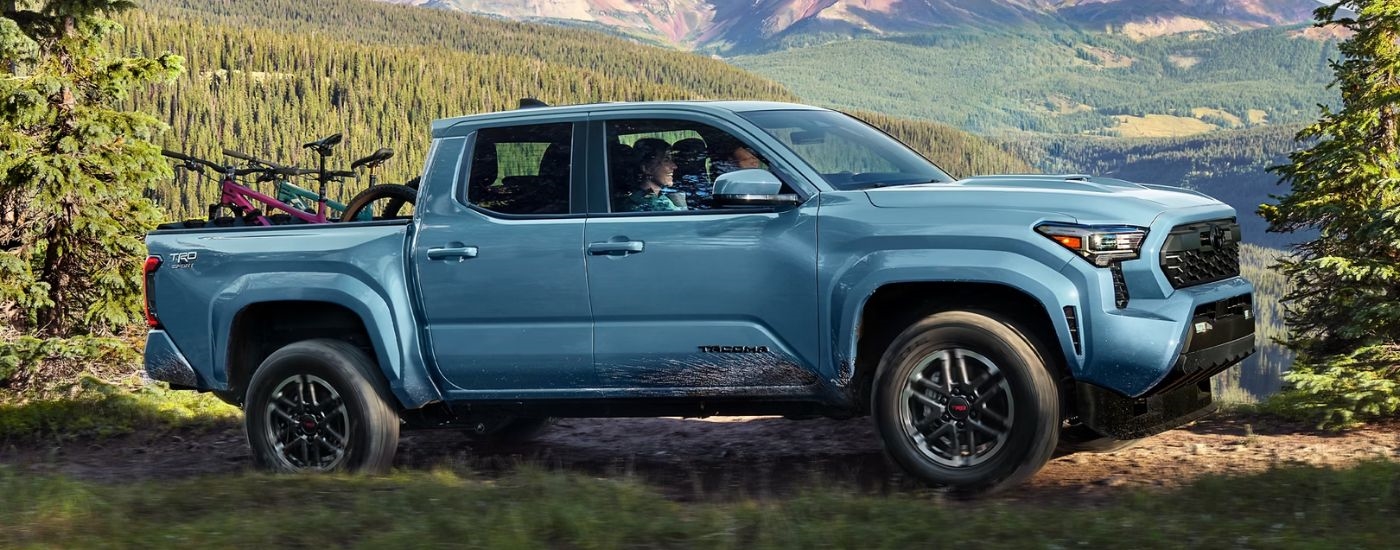 A blue 2026 Toyota Tacoma TRD Sport parked in forest.