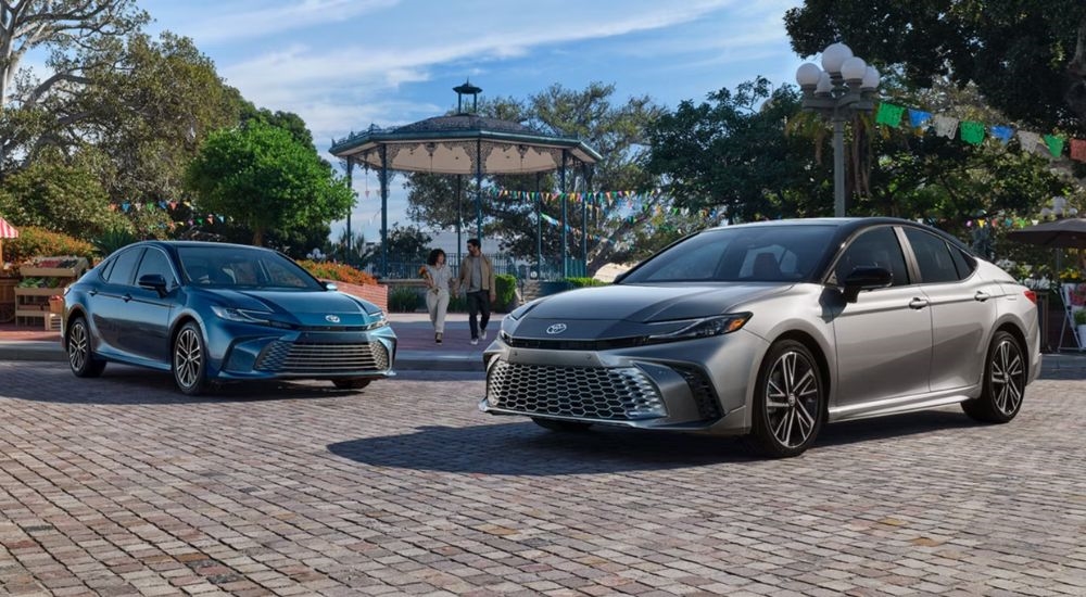 A blue 2026 Toyota Camry XLE parked by a gray 2026 Toyota Camry XSE.