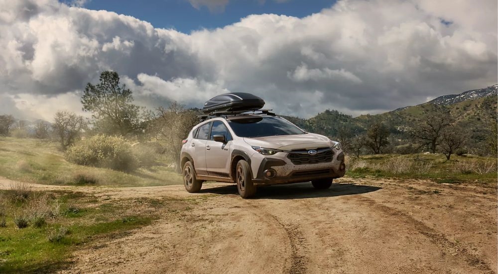 A white 2026 Subaru Crosstrek Limited Hybrid driving a dirt road.