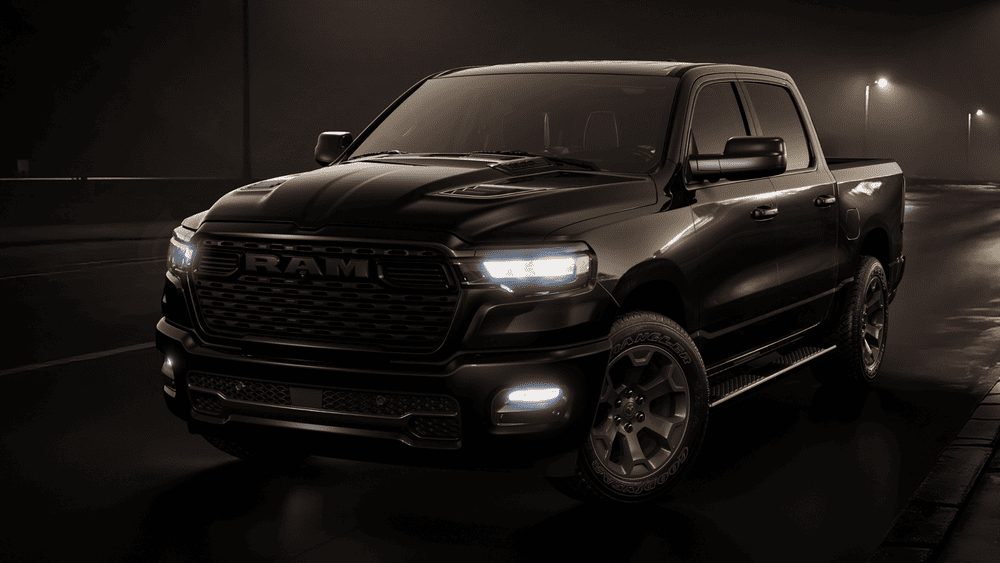 2026 Ram 1500 Express in Margate FL in all-black with blacked-out RAM grille, LED headlights, crew cab body, and dark alloy wheels photographed at night under urban lighting