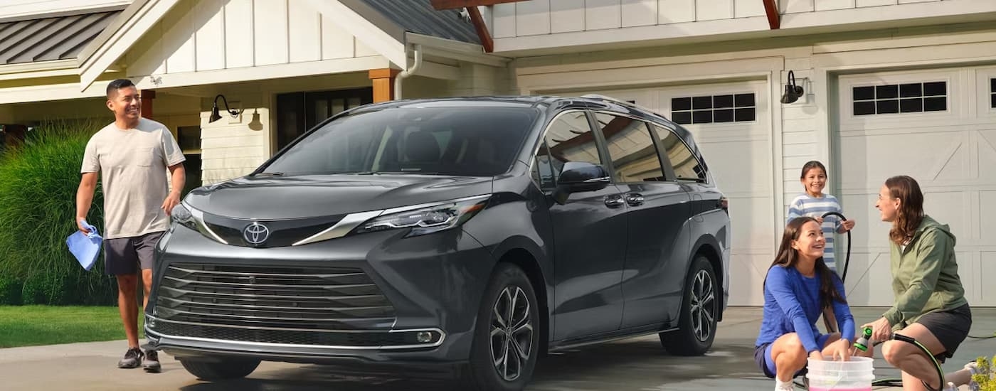 Grey 2026 Toyota Sienna parked in a driveway with a family washing it.