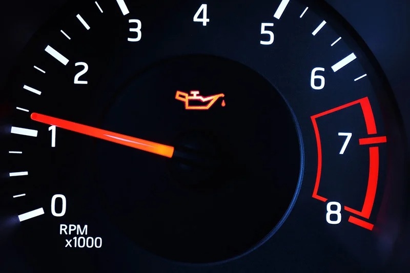 An illuminated car tachometer with the oil warning light on, showing 1,000 RPM.