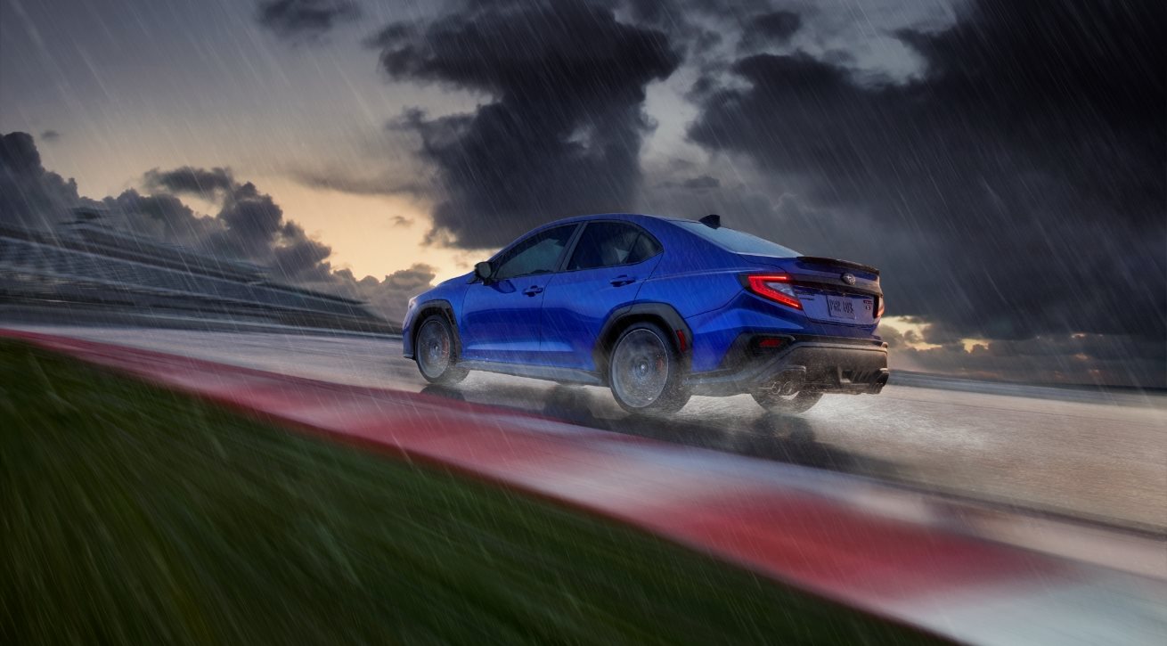 A blue Subaru WRX on a wet racetrack
