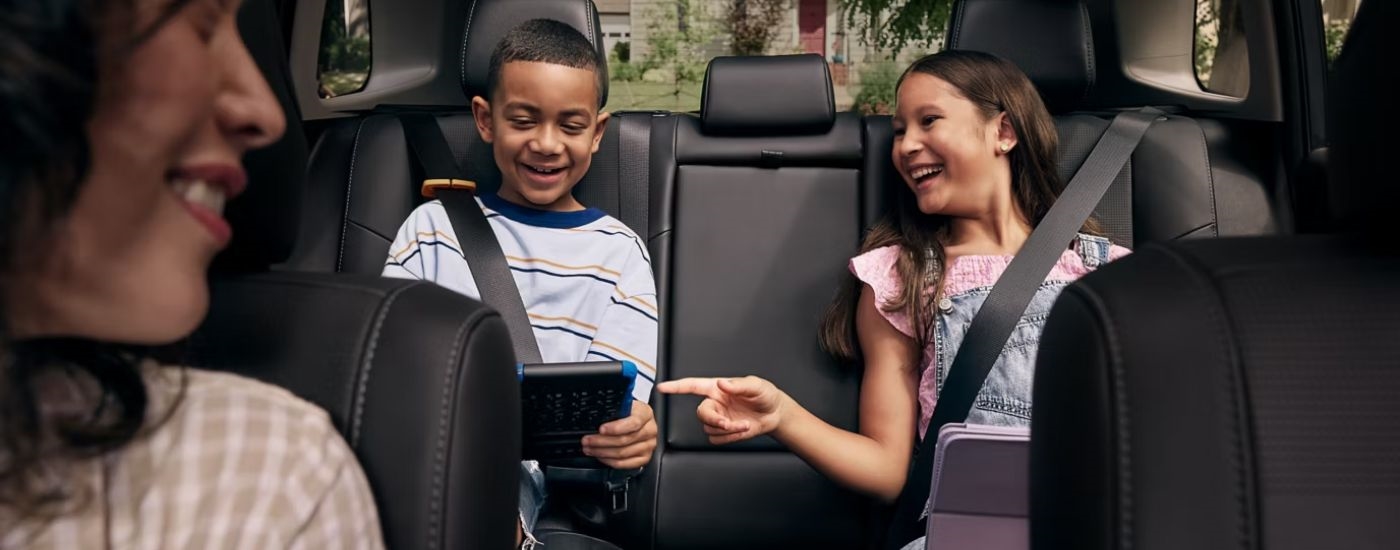 The interior of a 2026 Toyota RAV4 with kids in the backseat and a mother in the front passenger seat.