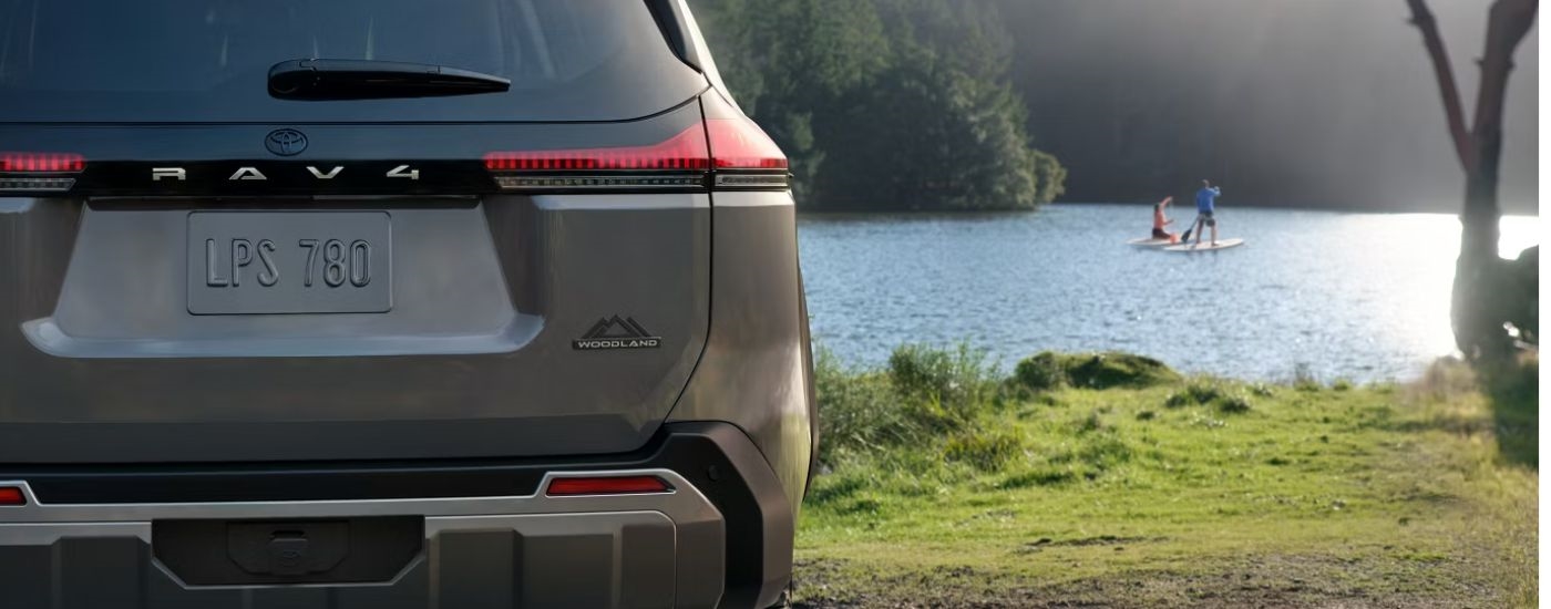 Brown 2026 Toyota RAV4 Woodland rear view while parked near a lake.
