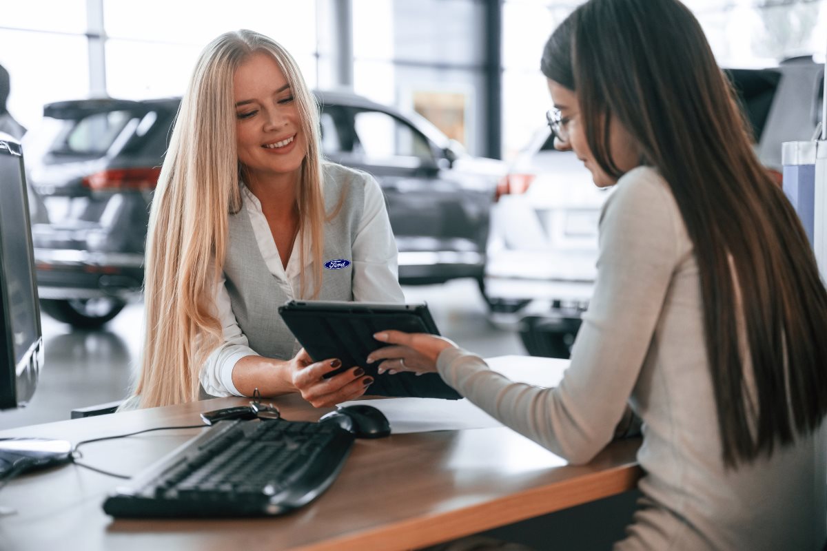 Customer reviewing financing options with a Ford dealership representative using a tablet in a showroom.