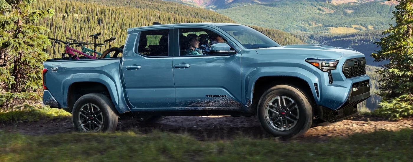 Blue 2026 Toyota Tacoma driving on an off-road trail.