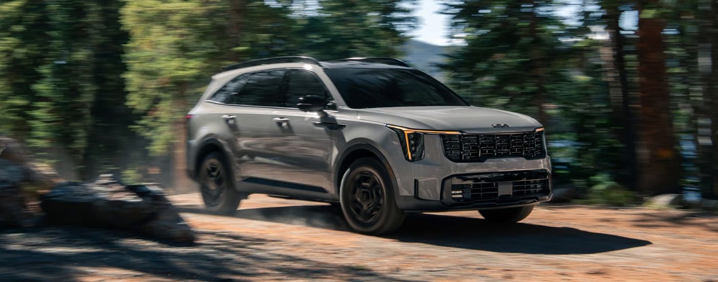 Grey 2026 Kia Sorento driving through the woods on a trail.