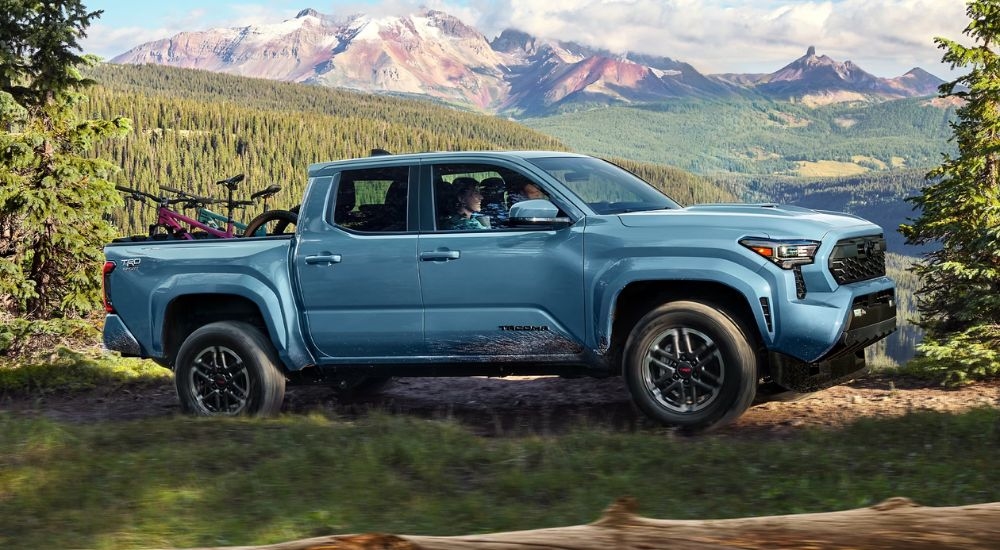 A blue 2026 Toyota Tacoma TRD Sport driving a trail.