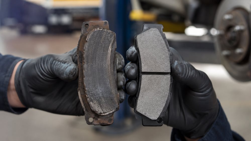 Honda technician comparing a worn brake pad with a new Genuine Honda brake pad at Honda Libertyville