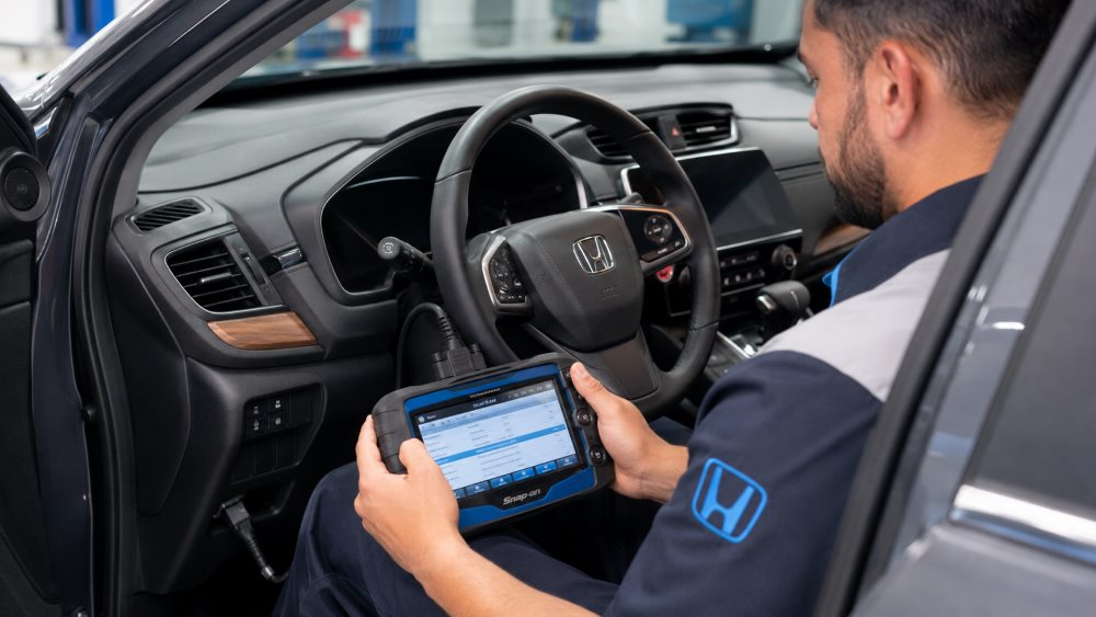 Technician reading Honda CR-V diagnostic trouble codes with a scan tool at Brickell Honda
