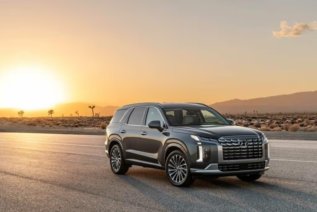 The 2025 Hyundai PALISADE flagship SUV parked on the street with the sunset behind it.
