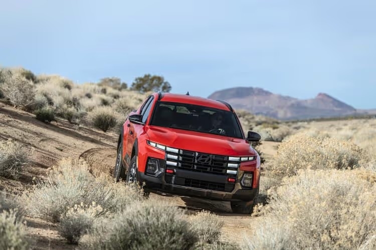 A 2025 Hyundai SANTA CRUZ navigating through a vast desert landscape under a clear blue sky.
