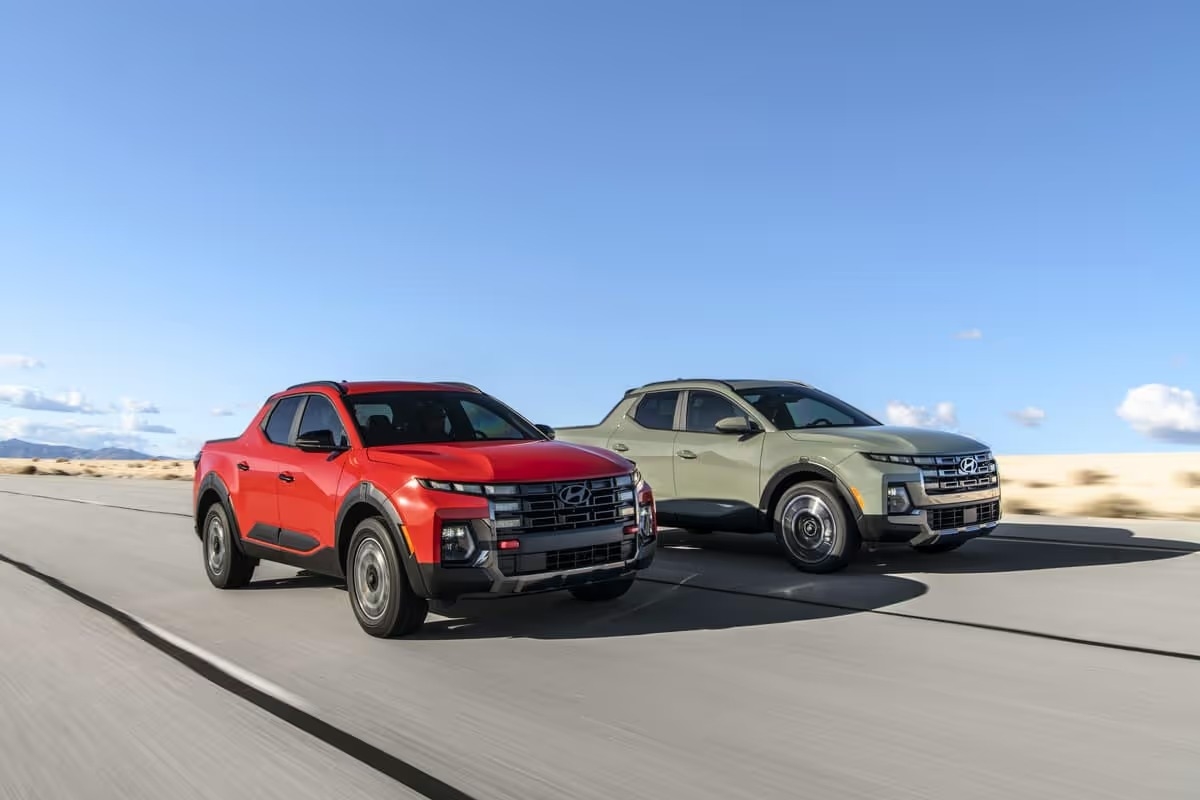 Two 2025 Hyundai Santa Cruz models, including the Santa Cruz XRT, are displayed driving on a scenic road, showcasing their rugged design.