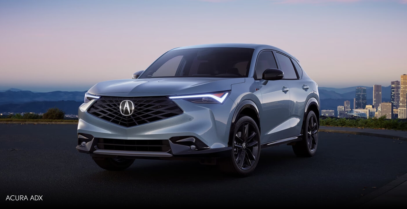 Exterior front three-quarter view of a silver Acura ADX parked against a distant city skyline.