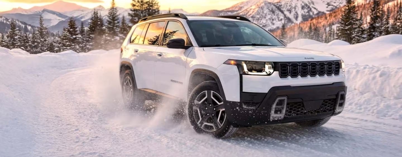 White 2026 Jeep Cherokee driving through snow