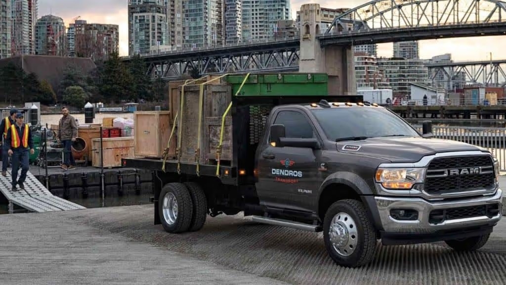 2022 ram chassis cab truck parked by a dock with loaded equipment in the back with workers walking towards the truck