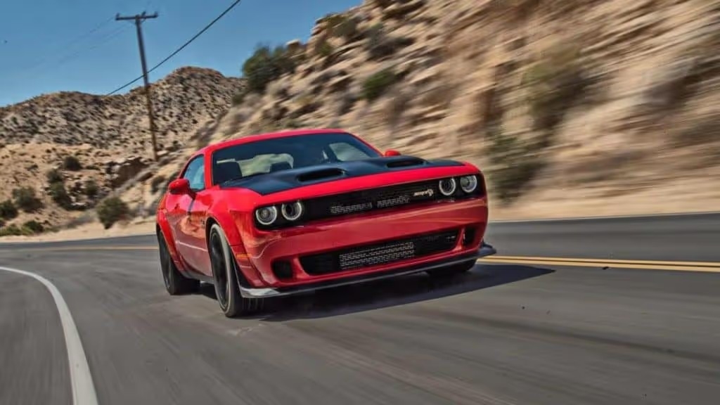 outdoor shot of a red 2022 dodge challenger driving through the street displaying speed