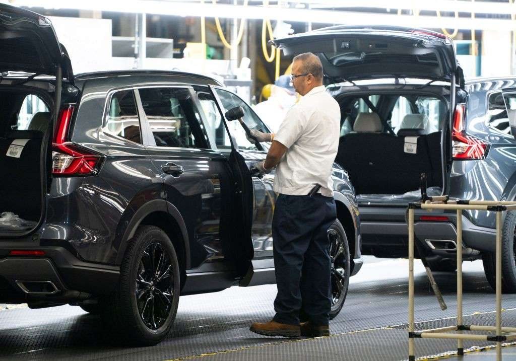 Honda service technician inspecting vehicle tire and rim in service bay in Akron, OH
