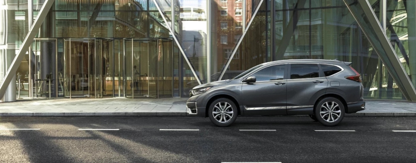 A gray 2022 Honda CR-V Hybrid Touring parked in front of a glass building.