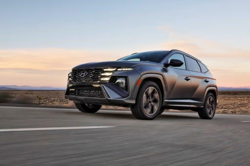 A 2025 Hyundai Tucson driving along a scenic road, showcasing its sleek design and modern features in motion.