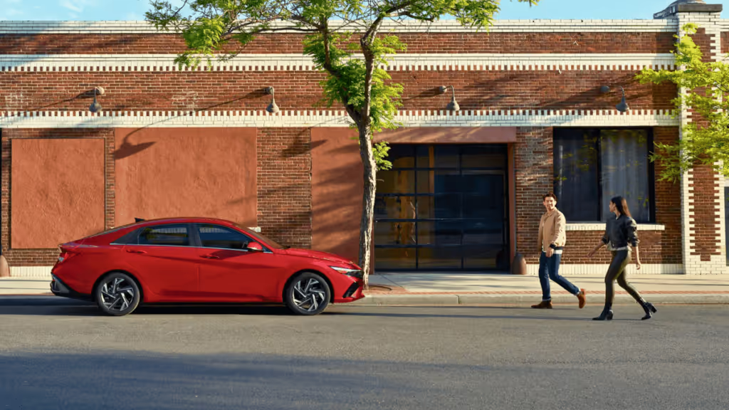 2024 Hyundai Elantra Limited with the Ultimate Red Exterior parked in front a brick building