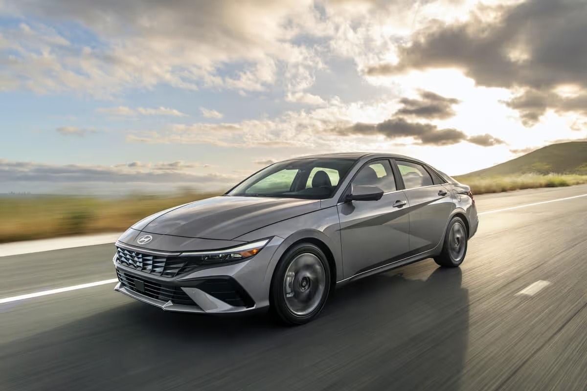 A 2025 Hyundai Elantra is cruising along a scenic road, showcasing its sleek design and modern features.