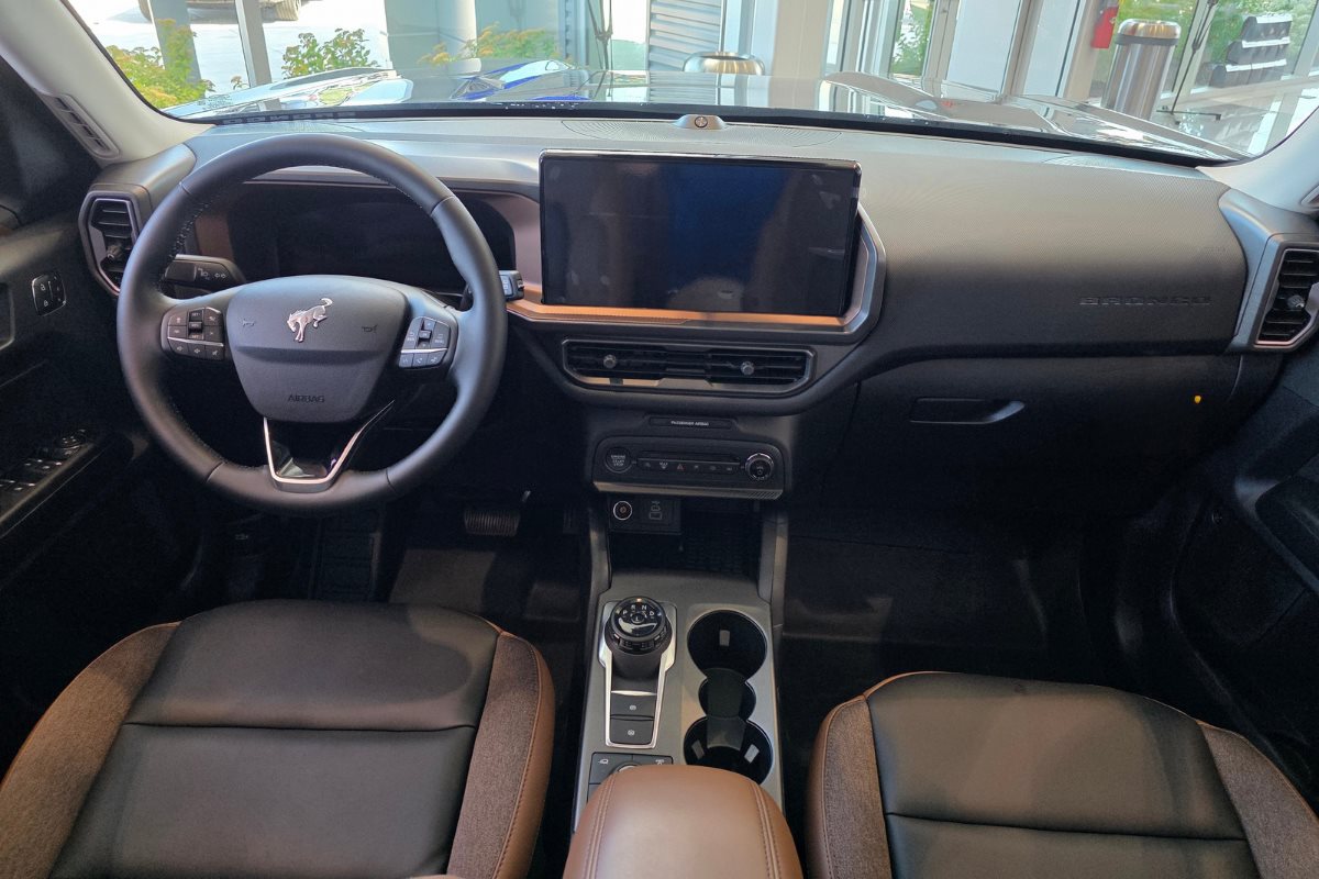 Driver-focused cockpit of the Ford Bronco Sport featuring a large touchscreen infotainment system, steering wheel controls, center console, and modern interior layout.