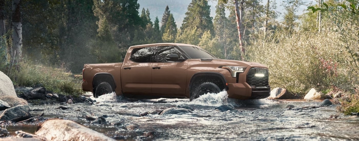 Brown 2025 Toyota Tundra TRD Pro driving through a creek