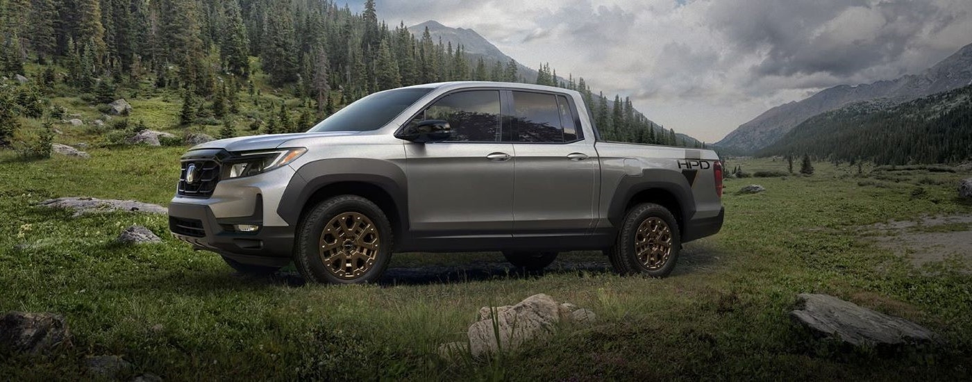 Grey 2023 Honda Ridgeline HPD parked in a grassy field.