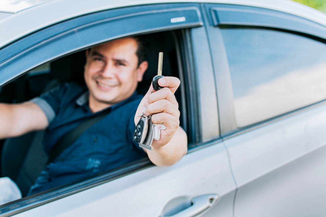 happy man in car holding keys