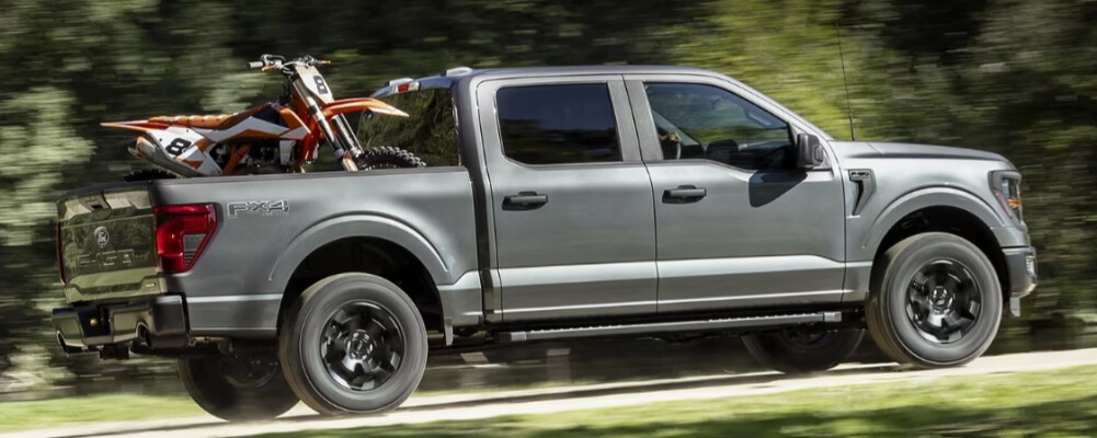 2024 Ford F-150 driving down the road with a dirt bike 