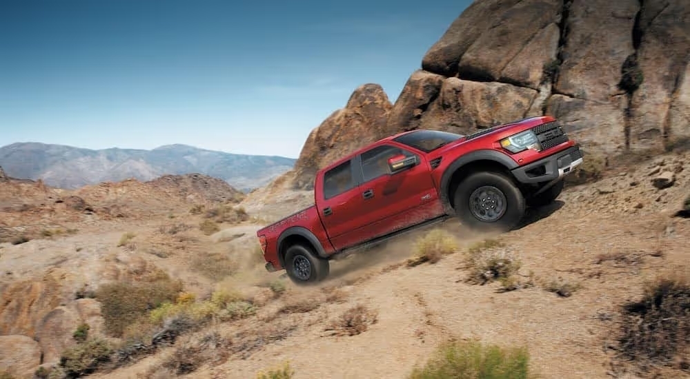 A red 2014 Ford F-150 Raptor is shown from the side.