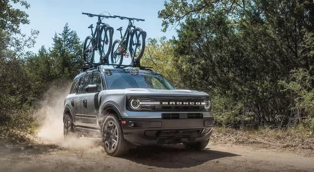 A light blue 2024 Ford Bronco Sport is shown driving off-road on a dirt path.