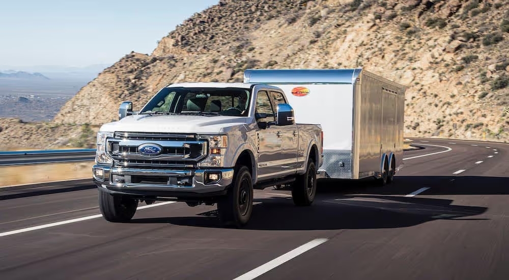 A white 2020 Ford F-350 is shown towing a trailer on a highway.
