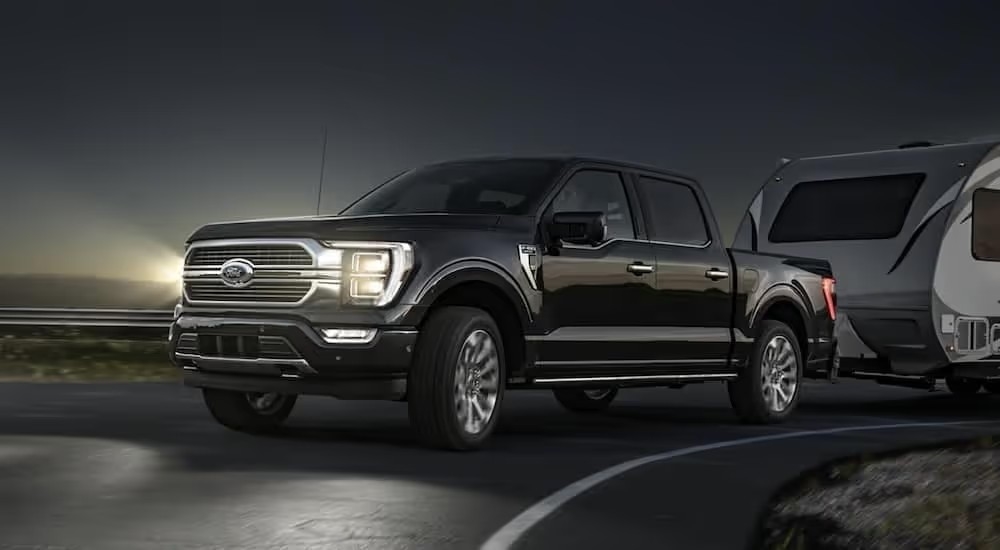 A black 2021 Ford F-150 towing a trailer at night